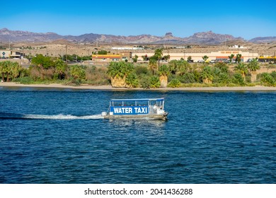 Laughlin, NV, USA – August 27, 2021: A water taxi on the Colorado River travels between casinos in Laughlin, Nevada, with a background view of Bullhead City, Arizona.