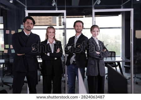 Laughter interrupts the formality for a moment while the rest of the team keeps its composed stance before the bright glass of the workspace in a bright modern coworking office.