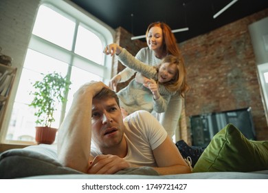 Laughting. Family spending nice time together at home, looks happy and cheerful. Mom, dad and daughter having fun, fighting with pillows. Togetherness, home comfort, love, relations concept.