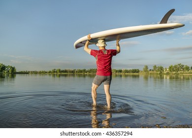 Launching Stand Up Paddleboard On A Calm  Lake In Northern Colorado With An Early Summer Scenery