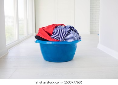 Laundry Basin With Dirty Clothes On Floor Near Windows