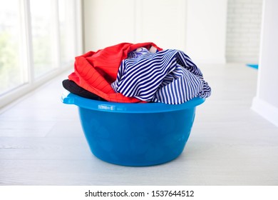 Laundry Basin With Dirty Clothes On Floor Near Windows