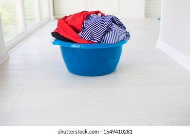 Laundry Basin With Dirty Clothes On Floor Near Windows