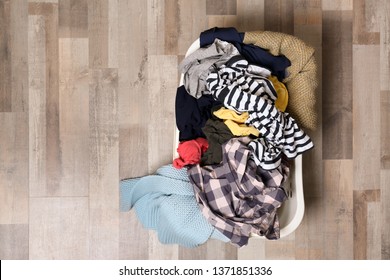 Laundry Basket With Dirty Clothes On Floor, Top View. Space For Text