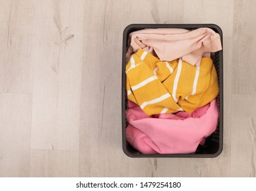 Laundry Basket With Dirty Clothes On Floor, Top View. Space For Text