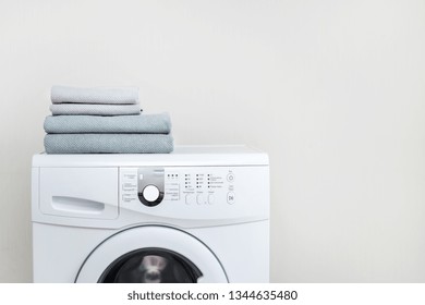 Laundry Concept. Cropped Photo Of White And Modern Washing Machine With Fresh Towel On Top Standing Isolated Inside Bright Apartment Light Interior