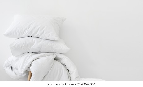 Laundry day and hotel service concept. Banner view of clean duvet and fresh pillows against white copy space background. Part of bedding on chair in apartment with comfort bedroom - Shutterstock ID 2070064046