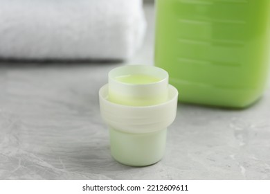 Laundry Detergent In Cap On Light Grey Marble Table, Closeup