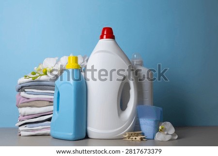 Laundry Detergents, stack of clothes and Washing Supplies on color Background