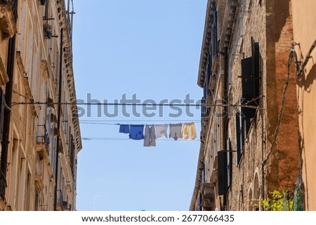 Laundry drying on clothesline between Venetian buildings. Colorful laundry hangs on a clothesline stretched between two old buildings in Venice, Italy, under a clear blue sky.