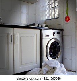 Laundry In Front Of Washing Machine In All White Kitchen