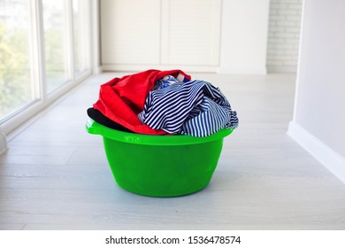 Laundry Green Basin With Dirty Clothes On Floor Near Windows