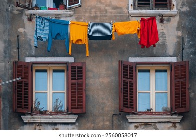 Laundry hangs against colorful facade, ancient mediterranean buildings in Rovinj, old town on croatian coast. Wall of old venetian house and clothes drying on rope outdoors. - Powered by Shutterstock