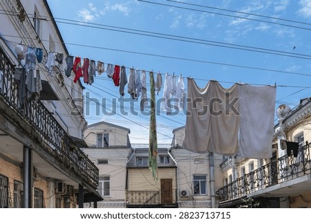 Laundry hung on lines between the galleries of residential courtyard balconies under a blue sky.