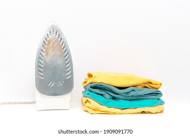 Laundry Pile Of Colorful Baby Clothing Isolated On White Background With Dirty Iron. Stack Of Trendy Color Clothes Close Up.