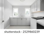 A laundry room with grey cabinets, white marble countertop, white washer and dryer, and a brown tiled floor. No brands or labels.