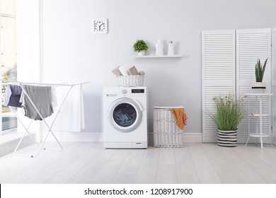 Интерьер прачечной со стиральной машиной возле стены