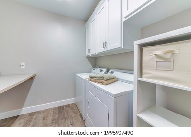 A laundry room with a washing machine, a dryer, and wooden cabinets for clothes - Shutterstock ID 1995907490