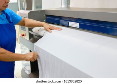 A Laundry Staff Is Ironing A Bedsheet With Industrial Ironing Machine. Shot Taken In The Factory.