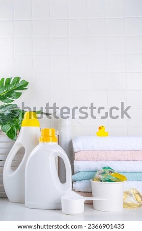 Laundry, washing and cleaning concept. Stack of clean towels, with various detergents - gels, capsules, powder, laundry basket  and cute rubber yellow duck, white bathroom background copy space