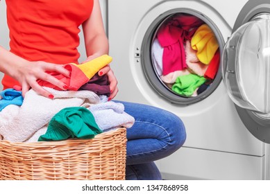  Lavandería. Joven carga la ropa en la lavadora de la cesta antes de lavarla.