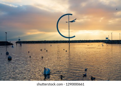 Lausanne, Switzerland - DECEMBER 2018: Dramatic tranquil silhouette  beautiful sunset at Geneva lake with atmosphere of swans on lake, embankment and Eole sculptural landmark in Lausanne, Switzerland.