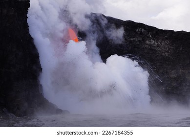 Lava falling down from high cliff into the ocean