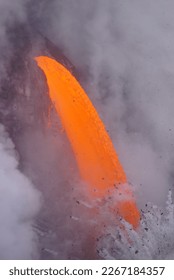 Lava falling down from high cliff into the ocean