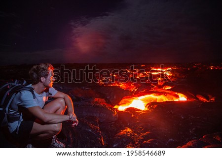 Lava flow man hiker on night hike watching magma erupting flowing from volcanic eruption in Kilauea volcano, Big Island, Hawaii travel. Long exposure.
