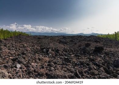 Lava tongue, lava valley, peak of Ostry Tobachik volcano in the clouds in Kamchatka. - Shutterstock ID 2046924419