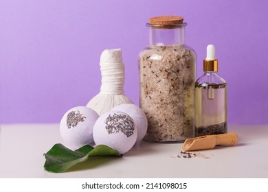 Lavender Bath Salt, Bath Bombs, Lavender Oil And Herbal Massage Balls On Purple Background. 