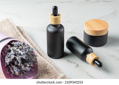 Lavender Essential Oil Skin Care Natural Cosmetics In Black Elegant Bottles On Marble Table. Set Of Bottles And Jar Cosmetology Cosmetics