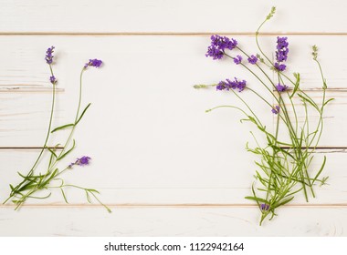 Lavender Flower Blossoms On Stems With Leaves As Borders Of Creamy Paper Card On Distressed White Shiplap Board Background With Room Or Space For Copy, Text Or Your Words.  A Horizontal Flat Layout