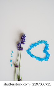 Lavender Flowers And Bath Salt. Blue Heart Of Lavender Bath Salt. Flat Lay Bath Salt, Spa Products And Lavender Flowers On White Background. Skin Care, Beauty Treatment Concept. Copy Space. 