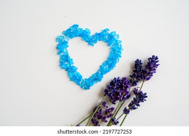 Lavender Flowers And Bath Salt. Blue Heart Of Lavender Bath Salt. Flat Lay Bath Salt, Spa Products And Lavender Flowers On White Background. Skin Care, Beauty Treatment Concept. Copy Space. 