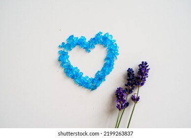 Lavender Flowers And Bath Salt. Blue Heart Of Lavender Bath Salt. Flat Lay Bath Salt, Spa Products And Lavender Flowers On White Background. Skin Care, Beauty Treatment Concept. Copy Space. 