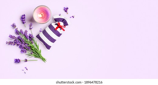 Lavender flowers and leaves bunch, sachet and candle creative layout on purple background. Top view, flat lay. Floral design element. Aromatherapy and herbal medicine concept