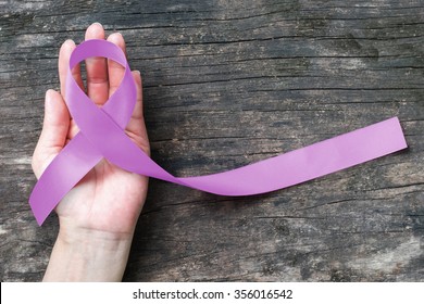 Lavender Purple Awareness Ribbon On People's Helping Hand Support With Aged Wood For World Cancer Day And National Cancer Survivor Month To Support Patient With All Kinds Of Tumor Illness
