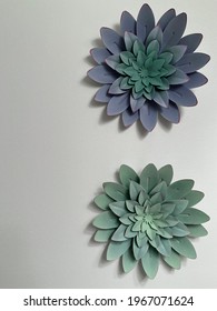 Lavender And Seafoam Green Metal Floral Succulent Wall Art Hanging On Plain Gray Painted Wall.
