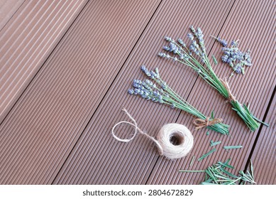 Lavender stems scissors twine ball on wooden background process of making bouquets. Dried organic lavender preparation workspace flat lay view composition. Handcraft hobby workspace with purple flower