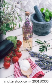 Lavender Vinegar In Bottle, Tomato, Egg-plant And Sage Plant On White Kitchen Table