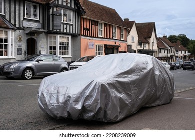 LAVENHAM, UK - SEPTEMBER 07 2022: Car Wrapped In A Plastic Car Cover Is Parked On A Street In Lavenham. Charming Half-timbered Houses In The Background