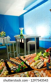 Lavish Sushi Buffet Table With An Ice Sculpture In The Background Sat On Top Of A Drinks Bar.