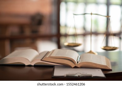 Law Books And Scales Of Justice On Desk In Library Of Law Firm. Jurisprudence Legal Education Concept.