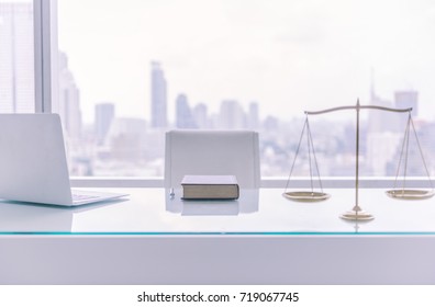 law books,computer and scales of justice on desk in lawyer office and city view.