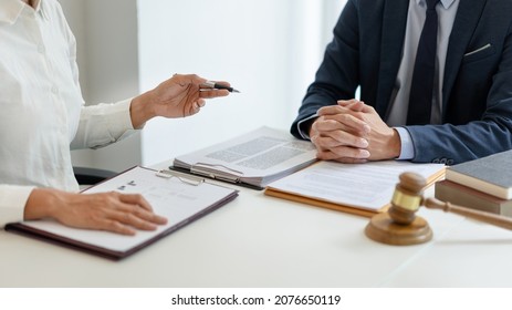 law concept The man in dark blue suit, a lawyer, sitting at his desk and trying to prepare to give law consultation to his customer with his assistance, the man in white shirt. - Shutterstock ID 2076650119