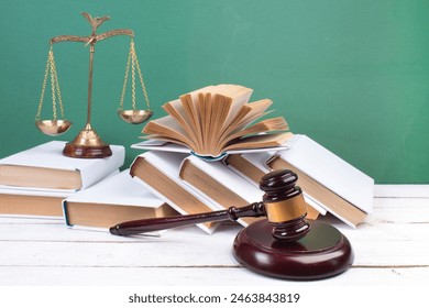 Law concept - Open law book, Judge's gavel, scales, Themis statue on table in a courtroom or law enforcement office. Wooden table, green background. - Powered by Shutterstock