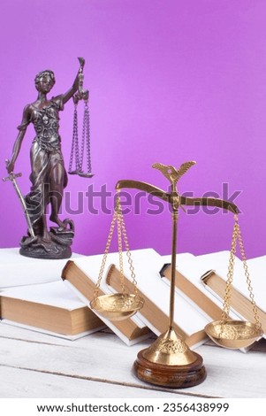 Law concept - Open law book, Judge's gavel, scales, Themis statue on table in a courtroom or law enforcement office. Wooden table, purple background