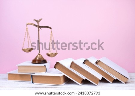 Law concept - Open law book, Judge's gavel, scales, Themis statue on table in a courtroom or law enforcement office. Wooden table, pink background