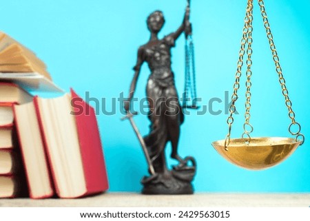 Law concept - Open law book, Judge's gavel, scales, Themis statue on table in a courtroom or law enforcement office. Wooden table, blue background.